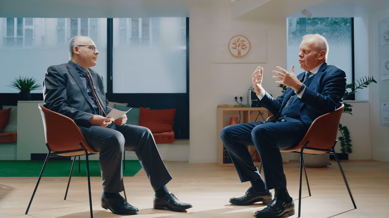 Plan large de l'interview : deux hommes assis face à face sur un plateau lumineux
