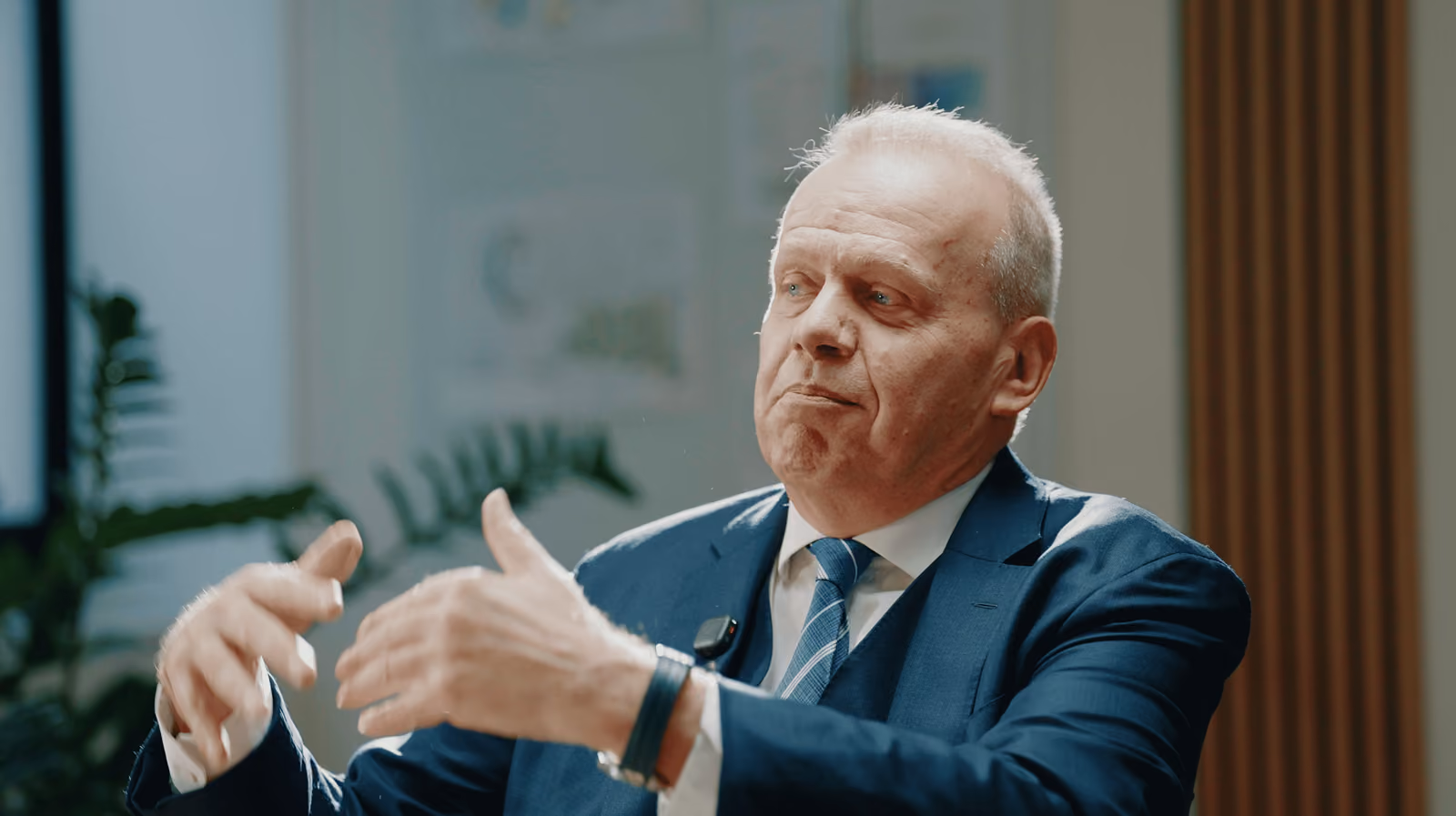 Intervenant en costume s'exprimant avec les mains pendant une interview multicaméra en faux direct