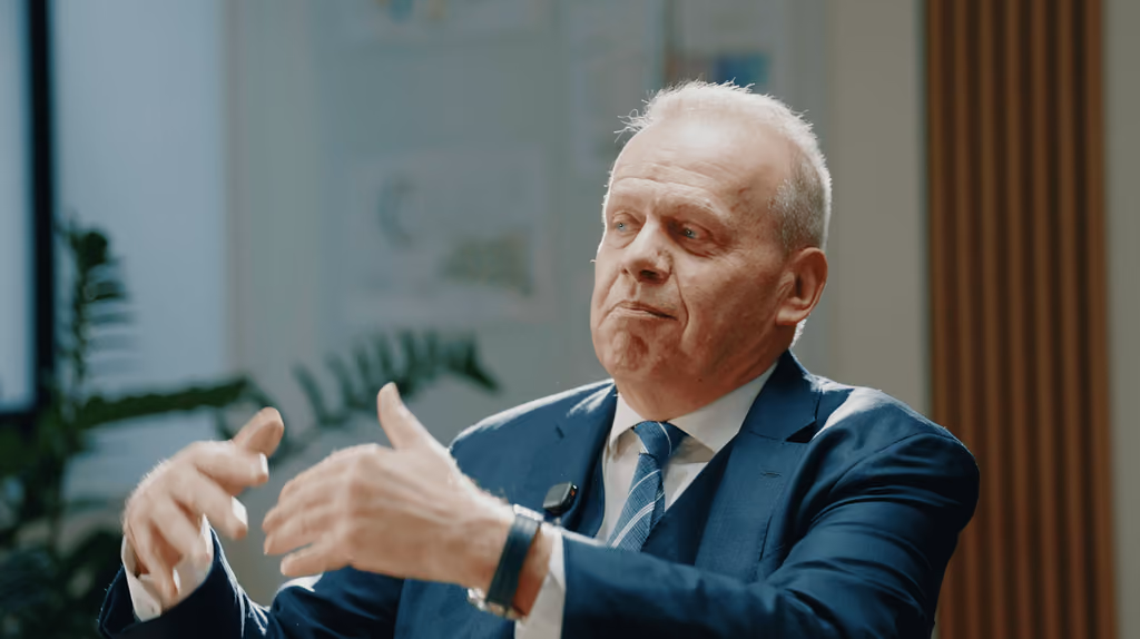 Intervenant en costume s'exprimant avec les mains pendant une interview multicaméra en faux direct