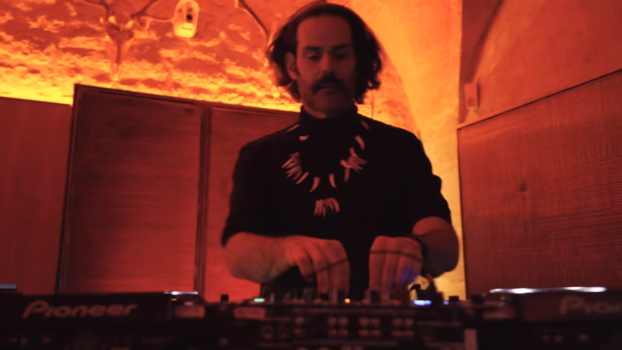 DJ mixant sous une voûte de pierre éclairée en rouge pendant La Fête de l'Ours