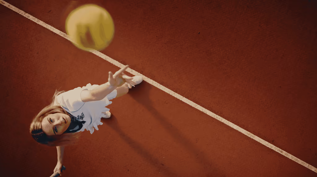 Joueuse de tennis allongée sur la terre battue, une balle au-dessus d'elle, vue du dessus — publicité Recycl'Ace