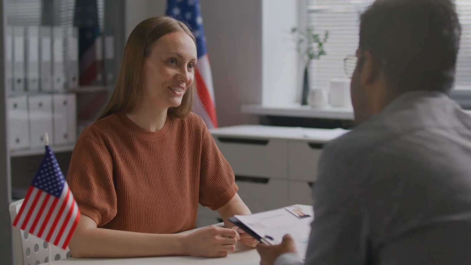 Un rendez-vous de travail à un bureau : une femme sourit à son interlocuteur.