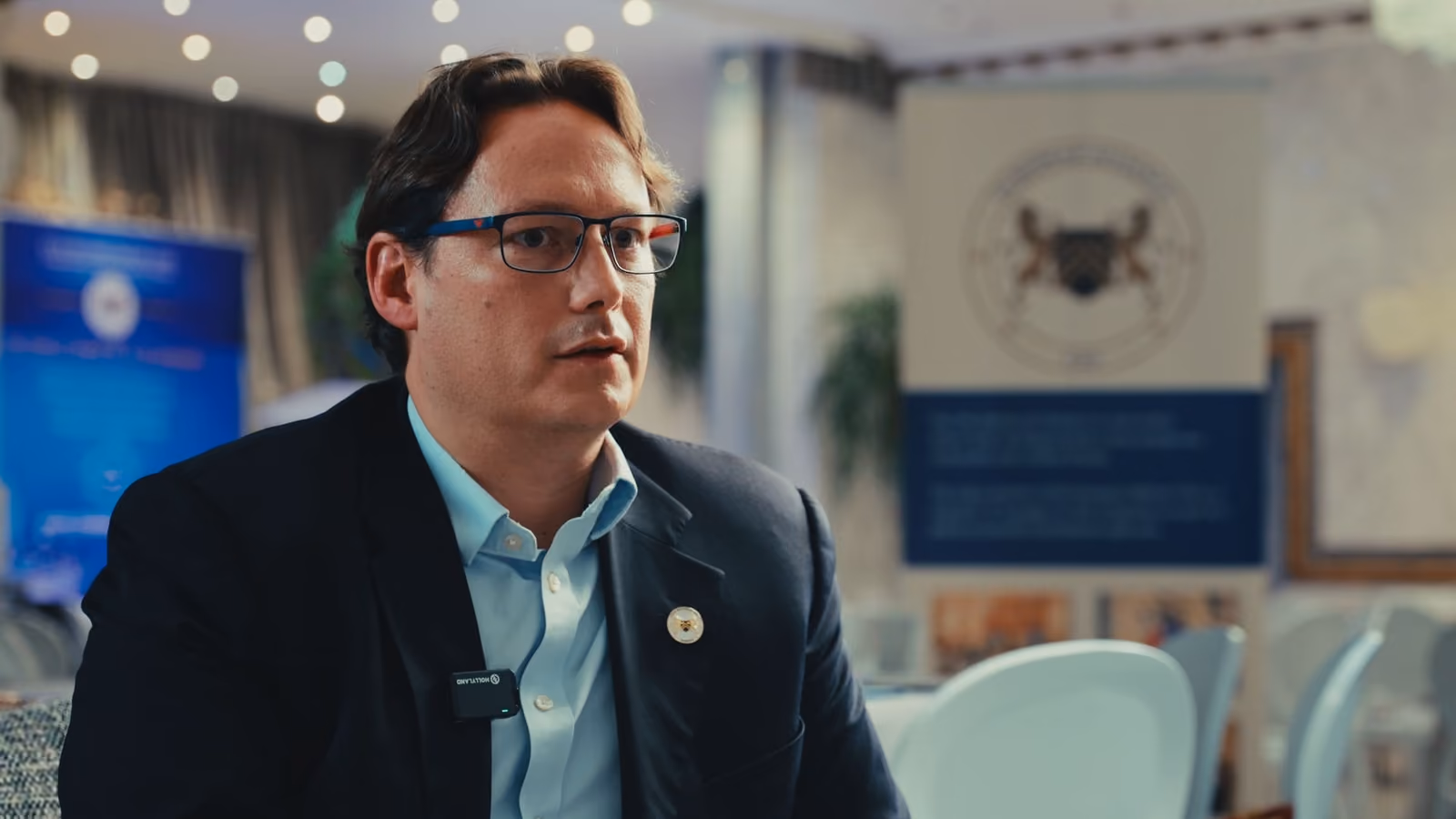Intervenant en veste sombre interviewé devant les visuels de l'événement Club Décision DSI